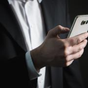 A stock image of a person holding a mobile phone (CANVA)