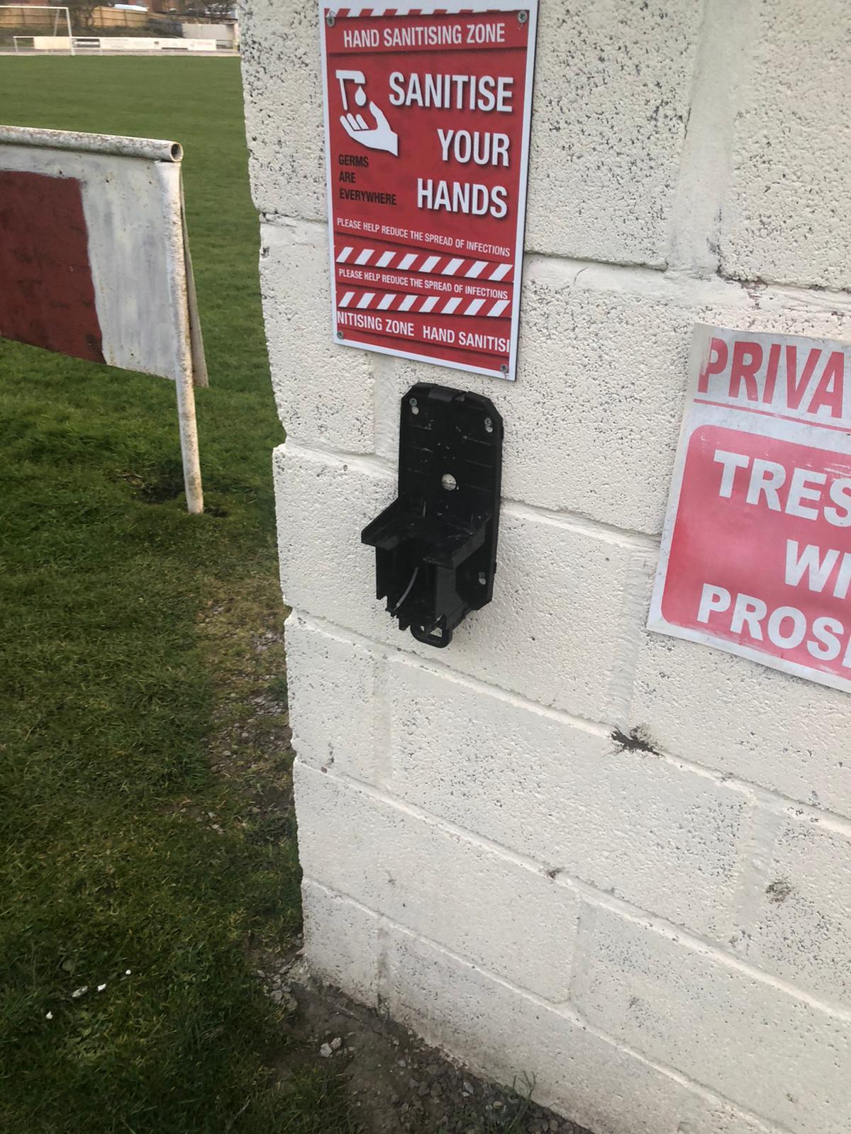 The broken hand sanitiser dispenser. 