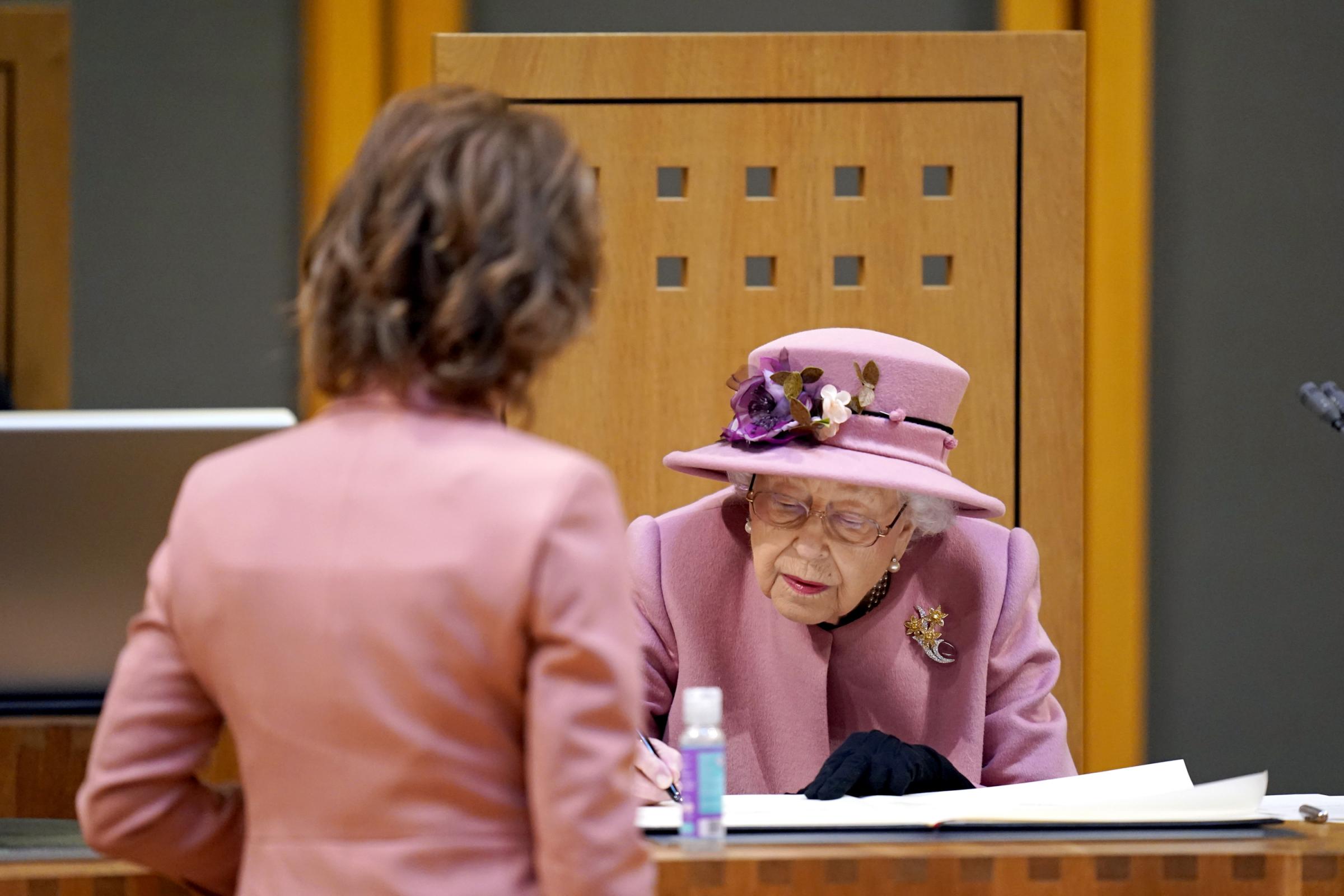 Queen Elizabeth II signs a document inside the Siambr (Chamber) during the ceremonial opening of the Sixth Senedd in Cardiff. Picture date: Thursday October 14, 2021.