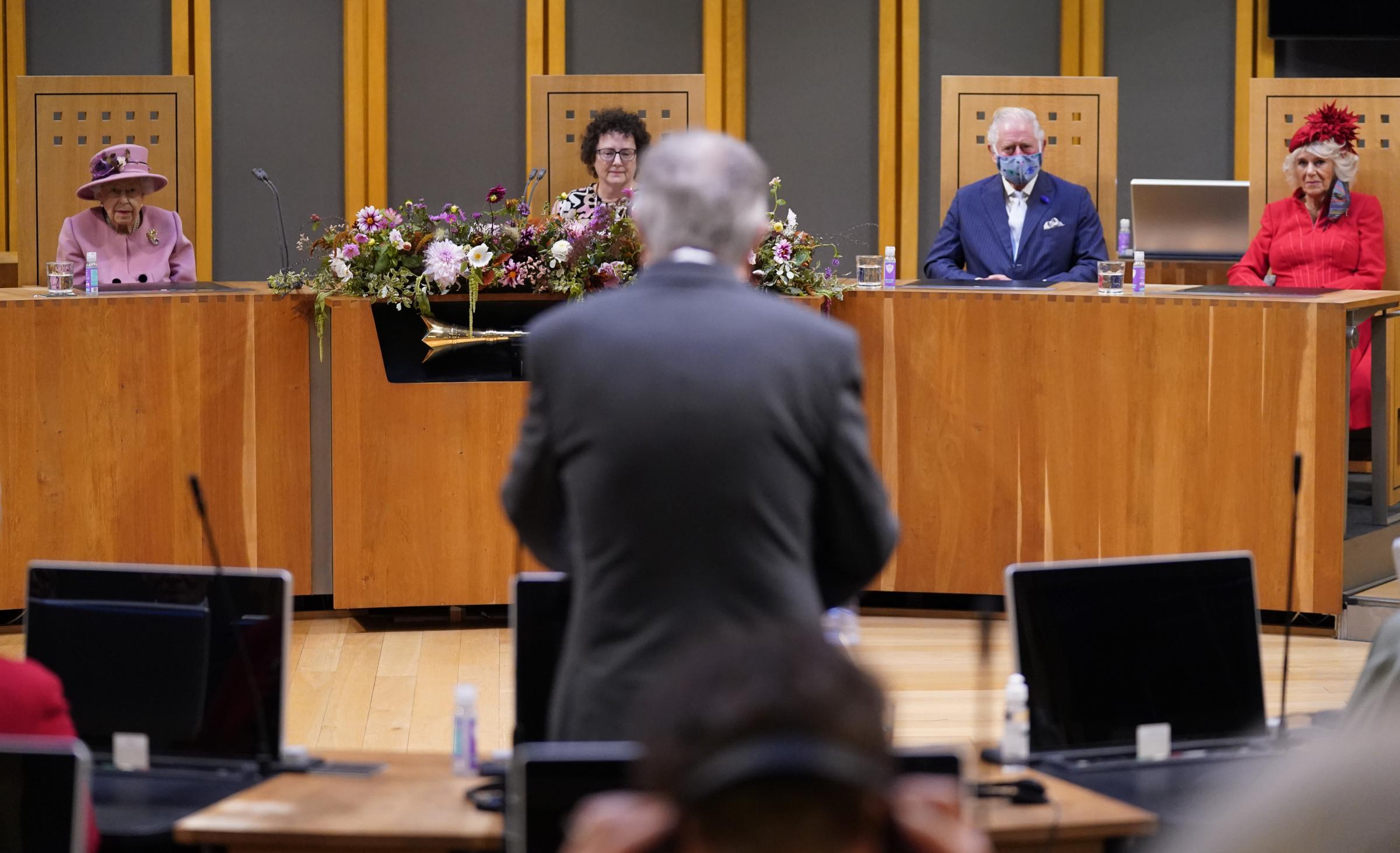 Queen Elizabeth II (left), Llywydd (presiding officer) Elin Jones, the Prince of Wales and Duchess of Cornwall (right) listen to a response by First Minister Mark Drakeford (back to camera) inside the Siambr (Chamber) during the ceremonial opening of the