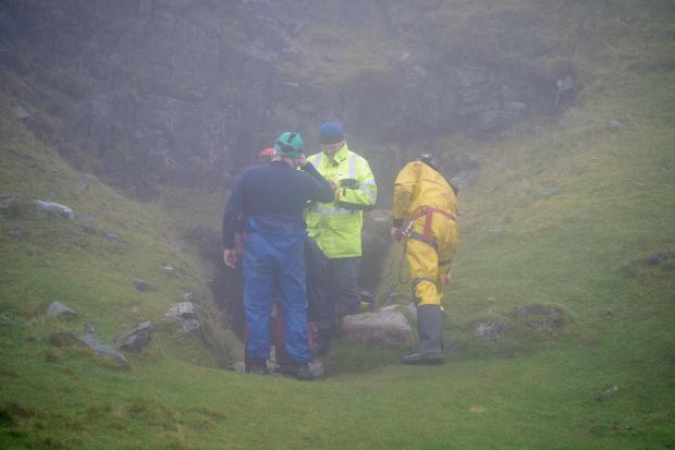 The Leader: Rescuers at the entrance of the Ogof Ffynnon Ddu cave system near Penwyllt, Powys in the Brecon Beacons, Wales, as rescue mission is underway to save a man who has been trapped inside a cave, after falling on Saturday. (PA)