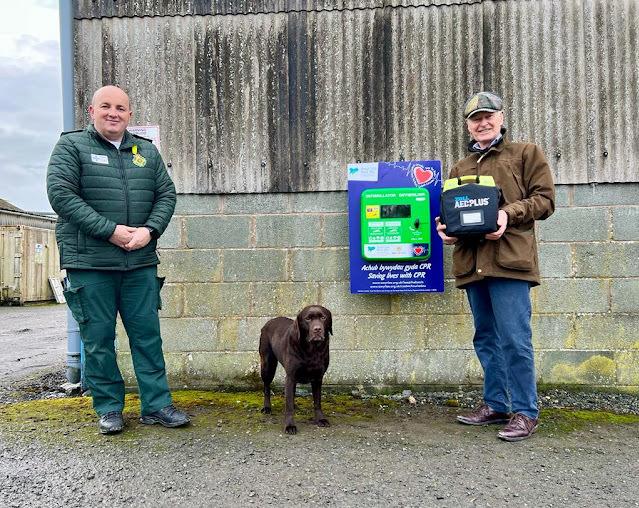 Tomos Hughes and Lord Newborough with the defibrillator unit in the Rhug Estate Farmshop car park.