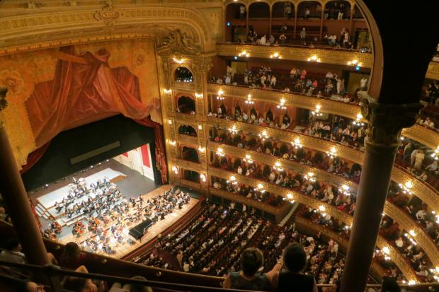 The Leader: A grand theatre with people watching an orchestra. Credit: Canva