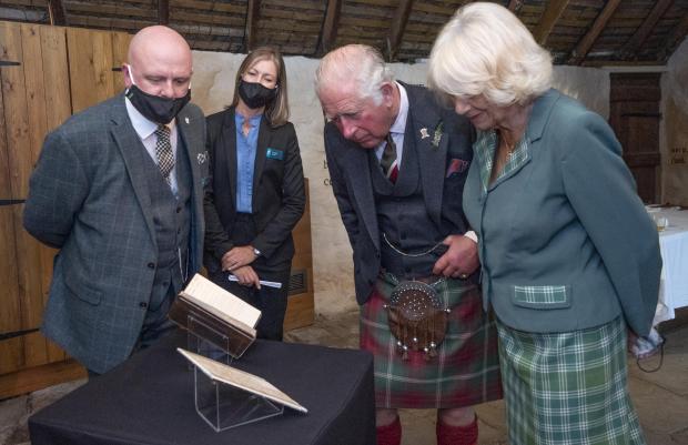 The Leader: The Prince of Wales and the Duchess of Cornwall, known as the Duke and Duchess of Rothesay when in Scotland, take a look at the original manuscript of Auld Lang Syne during a visit to Robert Burns' Cottage in Alloway, South Ayrshire. Photo via PA/Jane Barlow.