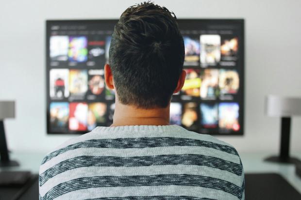 The Leader: A man watching a smart TV. Credit: Canva