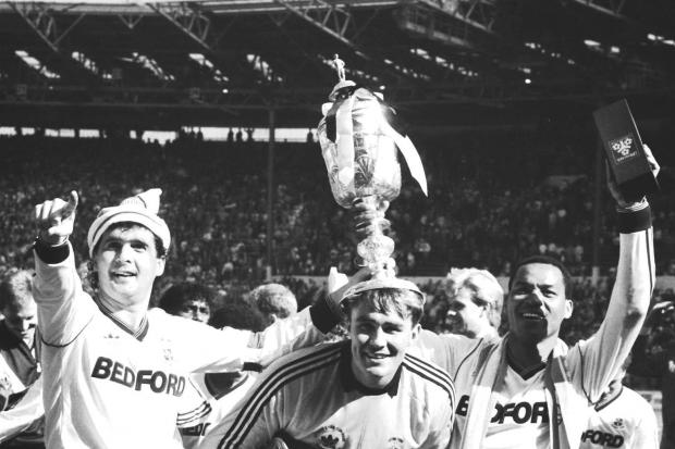 Luton Town captain Steve Foster (l) and two goal scorer Brian Stein (r) crown their goalkeeper Andy Dibble with the Littlewoods Challenge Cup after beating Arsenal 3-2 in a thrilling final.