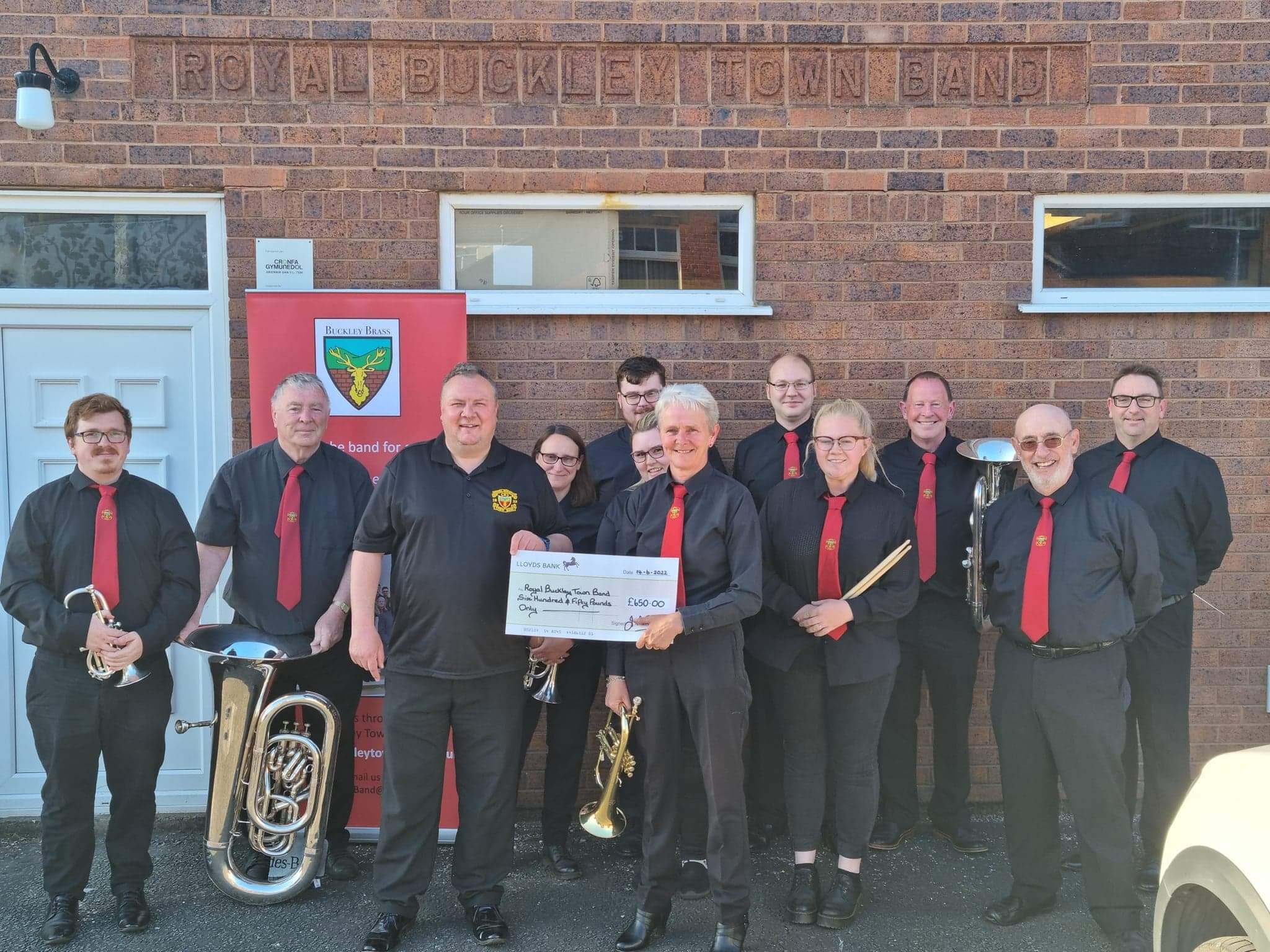 Julie Le Dain presents a cheque to Stephen Griffiths, chairman of Royal Buckley Town Band, with some of the players from Buckley Brass and conductor Steve Pugh-Jones.