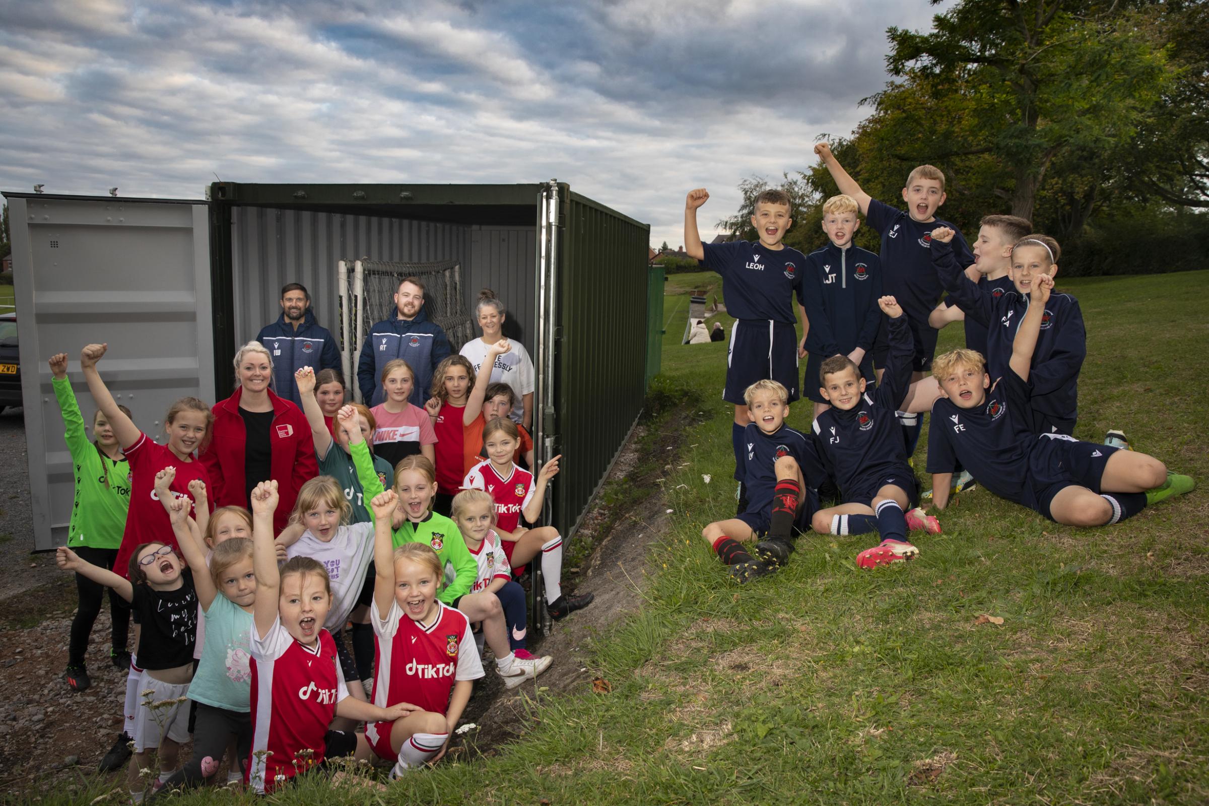Container Sales Centres Lisa James pictured with young Rhos Aelwyd junior footballers and their coaches, from left, Ian Williams, Arron Thomas and Lucy Davies, in front of their new equipment storage unit. Photo: Mandy Jones Photography.