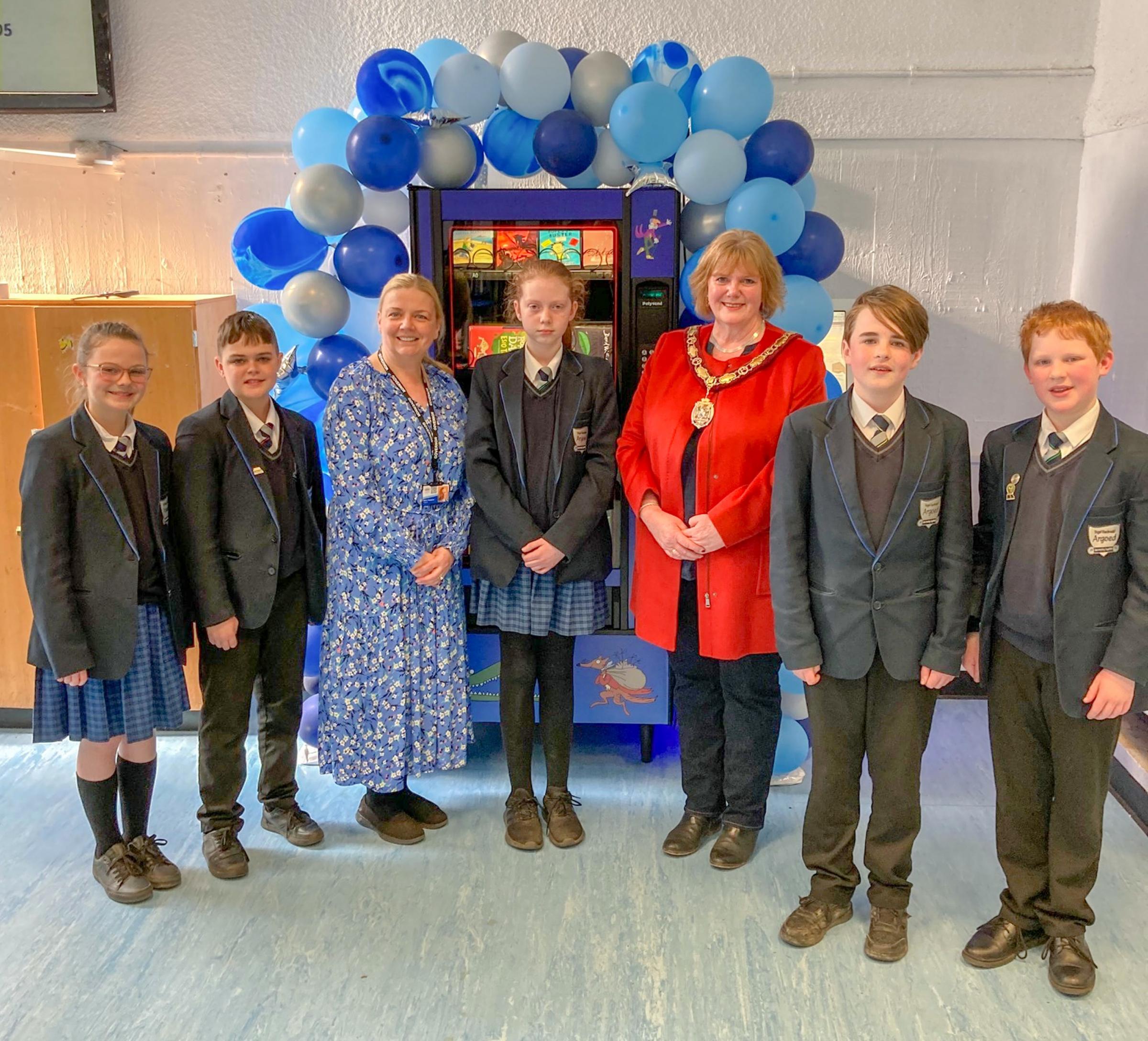 Laura Heywood and Cllr Mared Eastwood with students at the launch of the new book vending machine.
