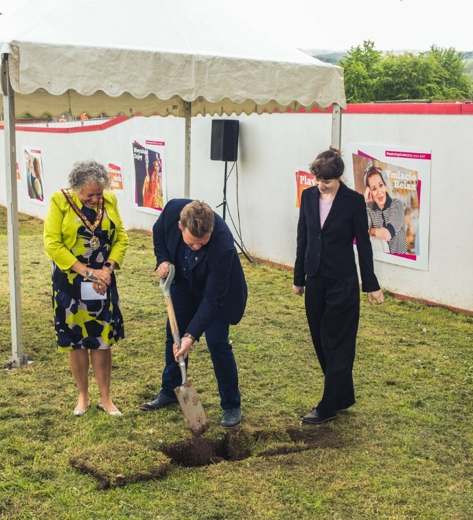 Chair of Flintshire County Council, Cllr Gladys Healey and artistic director Kate Wasserberg watch on as executive director Liam Evans-Ford buries the time capsule at Theatr Clwyd. Photo: Andrew AB Photography
