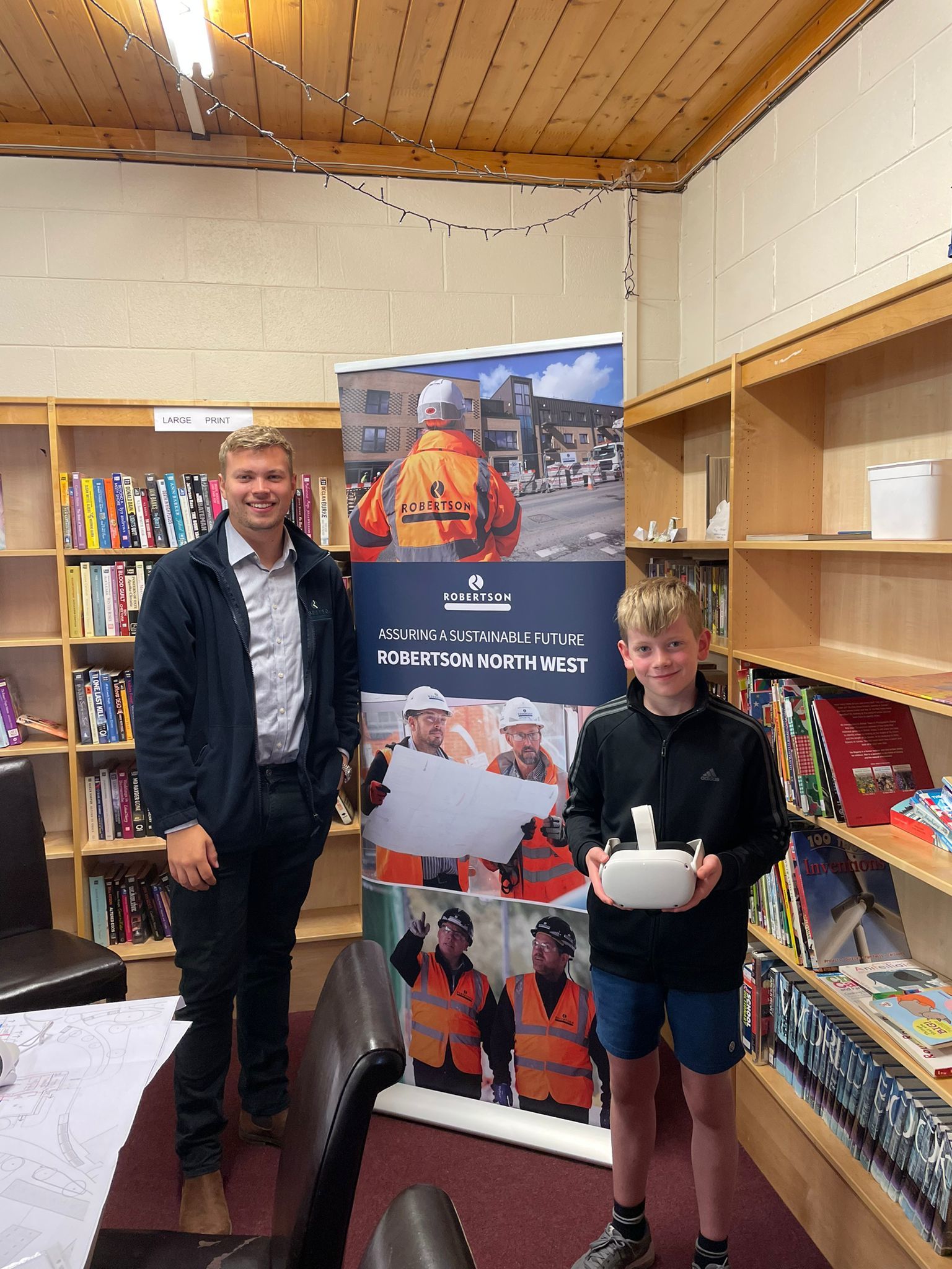 A pupil is about to visit the new school using a VR headset, pictured with Joe King, design co-ordinator, Robertson Construction.