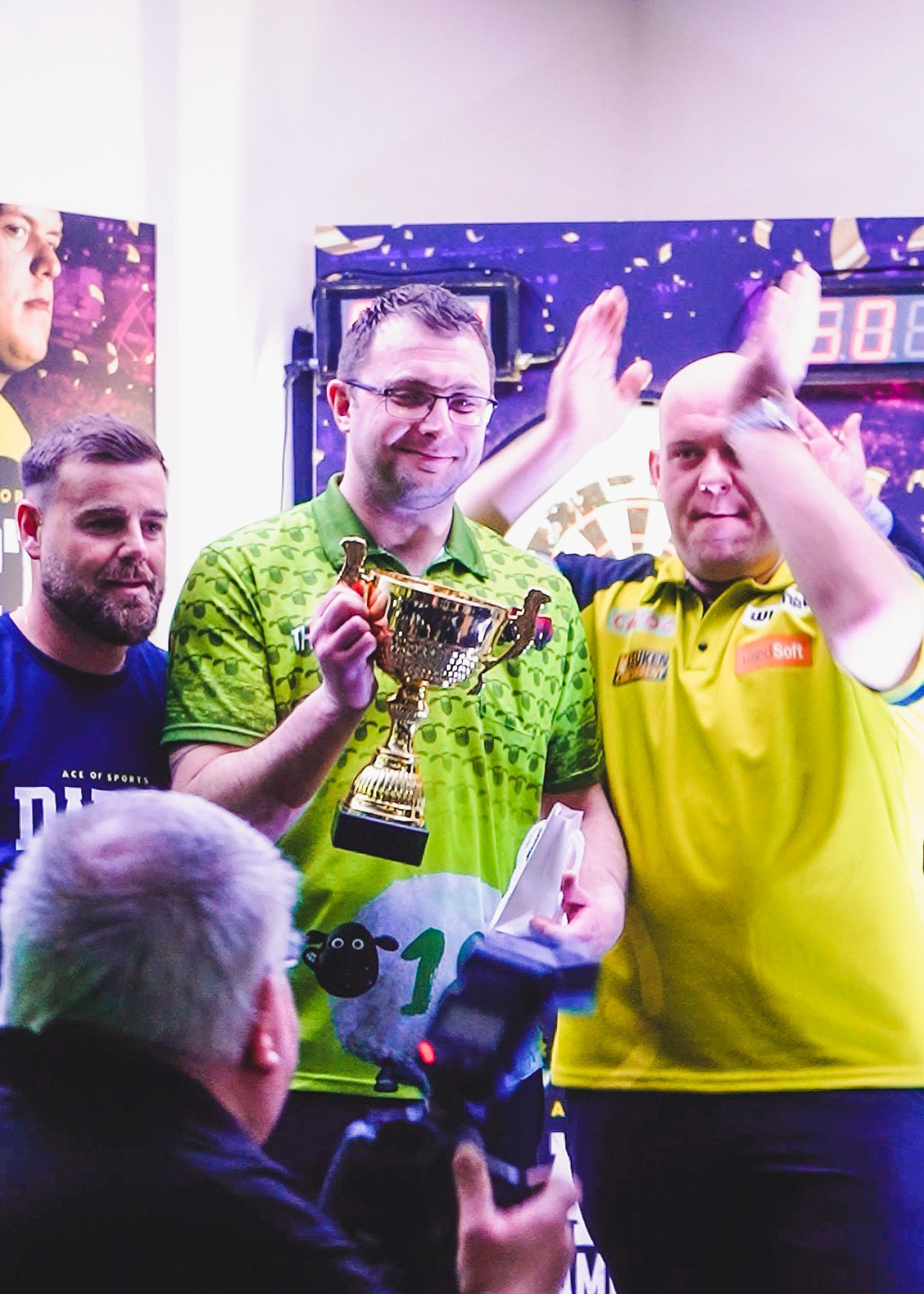 John Jones from Ace of Sports (left) and Michael van Gerwen (right) with Ace Of Sports Darts Championship 2023 winner Shaun Thompson.