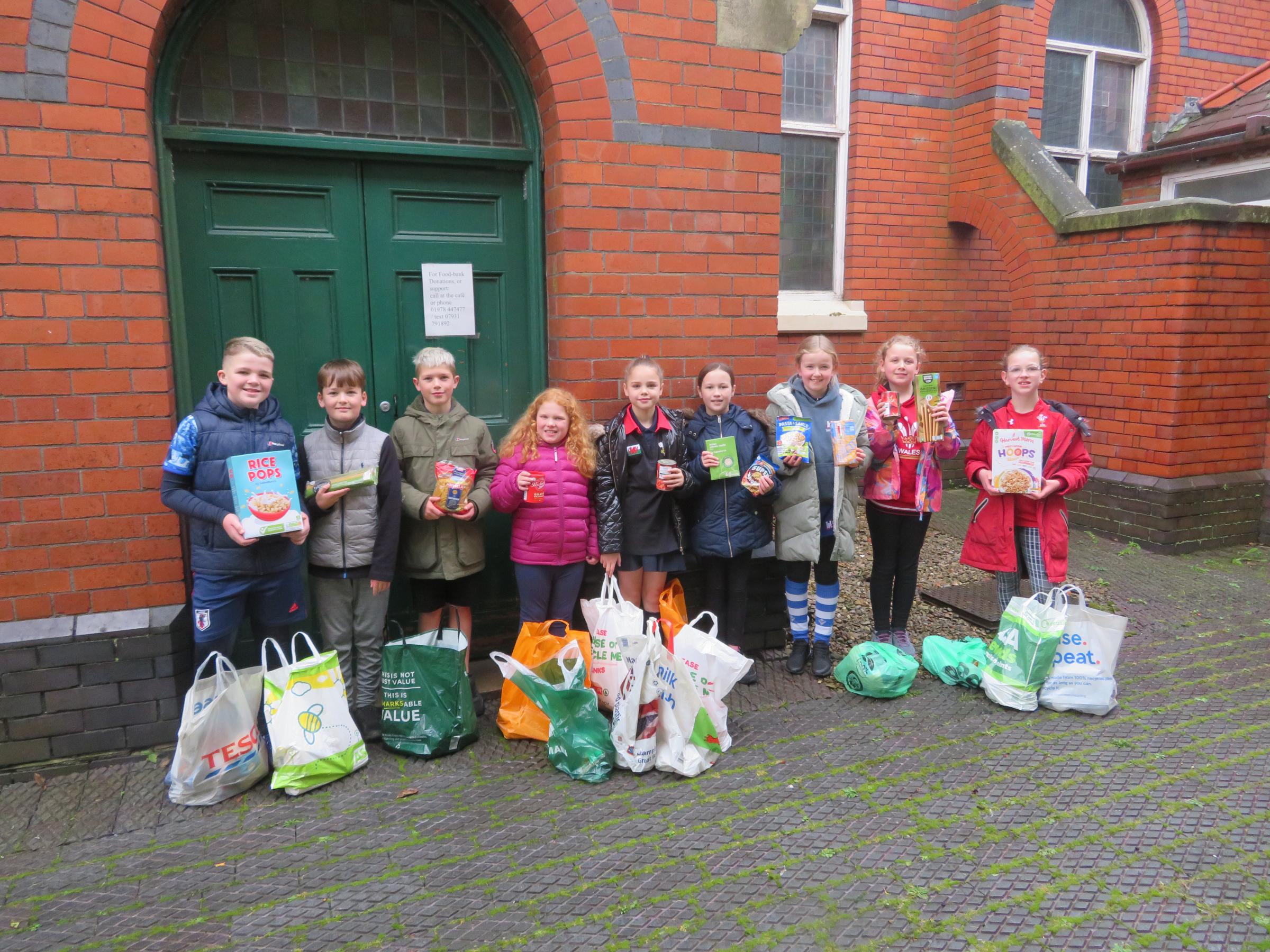 Ysgol I D Hooson school council members presenting food items following harvest donations.