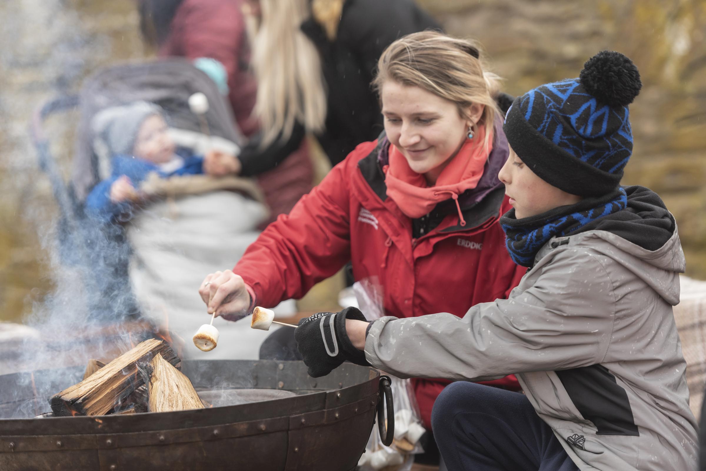Staff and visitors toasting marshmallows on the fire at Erddig, Wrexham. Photo: National Trust Images-Paul Harris