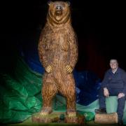 Talented chainsaw sculptor Paul Morris from the Pendine Park gardening and maintenance team with his latest masterpiece, the giant grizzly bear