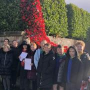 Children with the poppy waterfall at the Cefn Mawr Cenotaph.