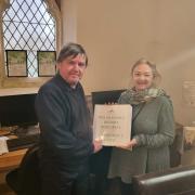 Adrian Howells, Wrexham Cemetery and Crematorium attendant, receives Welsh Family History Research: A Beginner's Guide from Friends of Wrexham Cemetery ice-chair and genealogy assistant, Madeleine Dale.