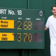 USA's John Isner stands by the final score board reading 70-68 as he celebrates victory over France's Nicolas Mahut in their record breaking match on Court 18 during Day Four of the 2010 Wimbledon Championships at the All England Lawn Tennis